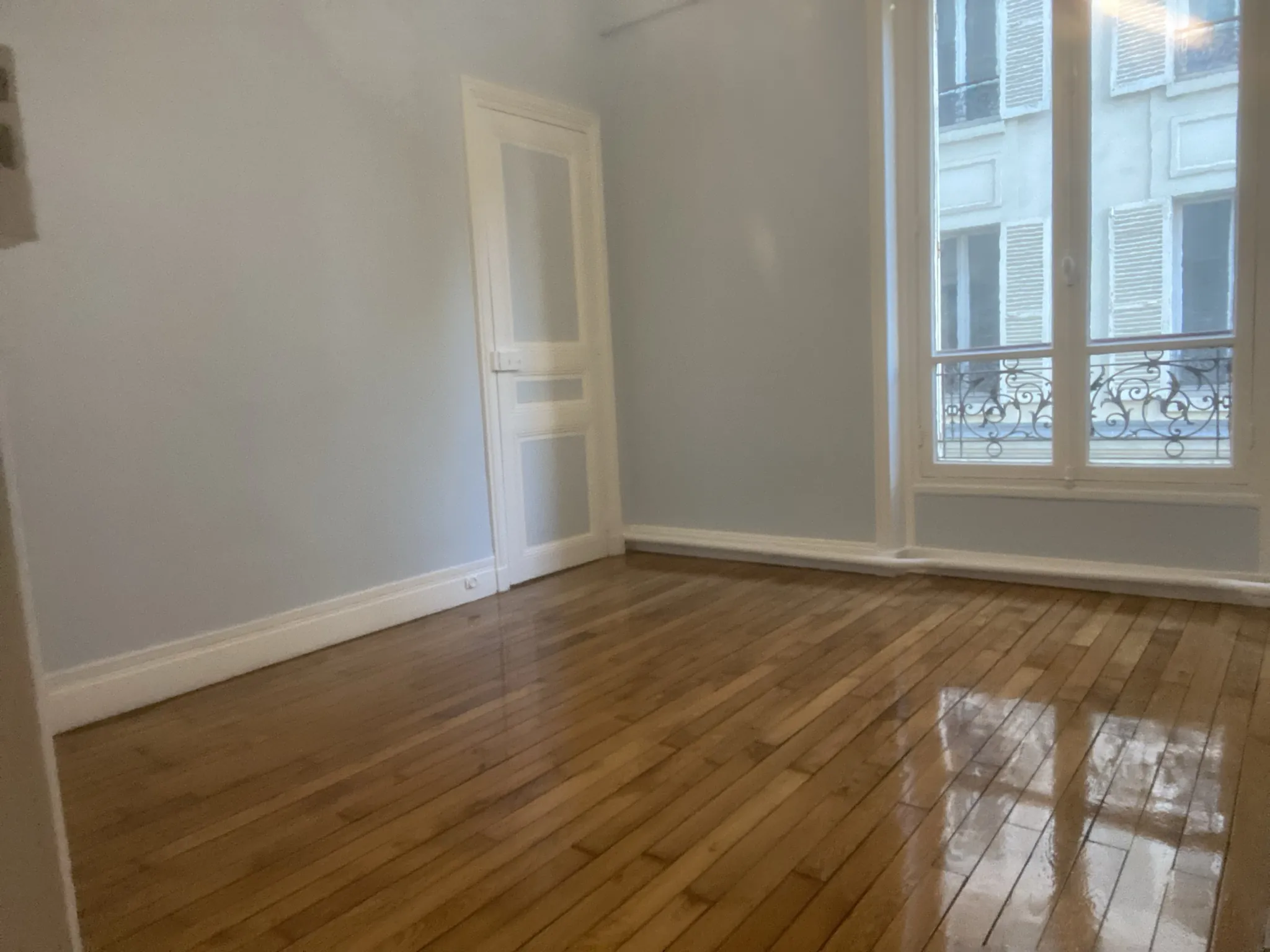 Chambre rénovée dans le 16e : murs repeints en gris-bleu clair, parquet en lames droites vitrifié satiné, photographié juste après l'application